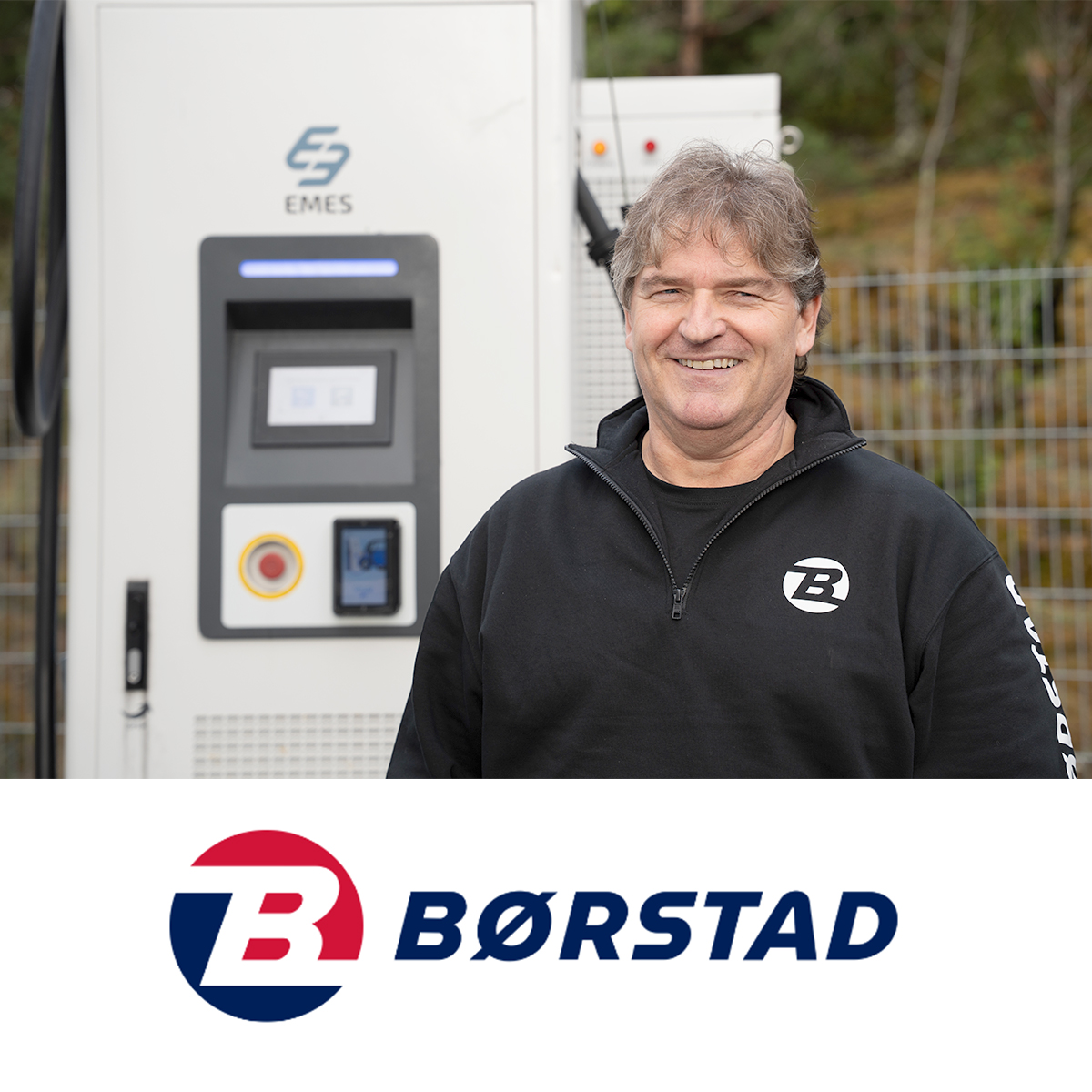 Person fra Børstad står foran en EMES-ladestasjon som brukes til elektriske lastebiler.